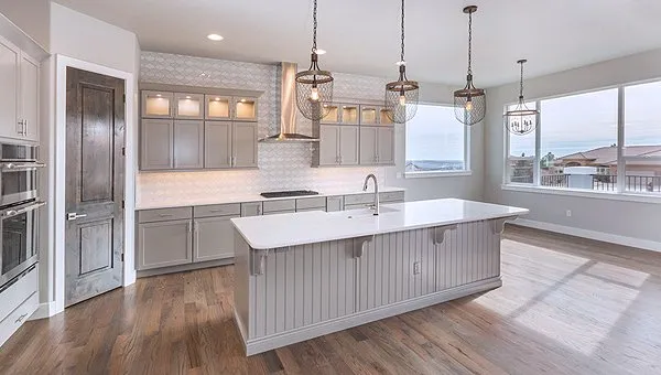 A kitchen with white cabinets and wooden floors.